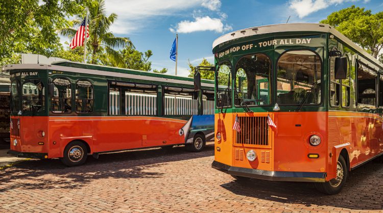 Tourists travel on historic, orange Trolley Buses of Key West, Florida